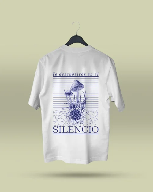 Camiseta blanca unisex con ilustración artística de hongos y raíces, acompañada de la frase poética Te descubrirás en el silencio. Ropa original hecha en Colombia con mensajes reflexivos y diseño exclusivo para quienes buscan prendas únicas con significado. Con envío a todo Colombia