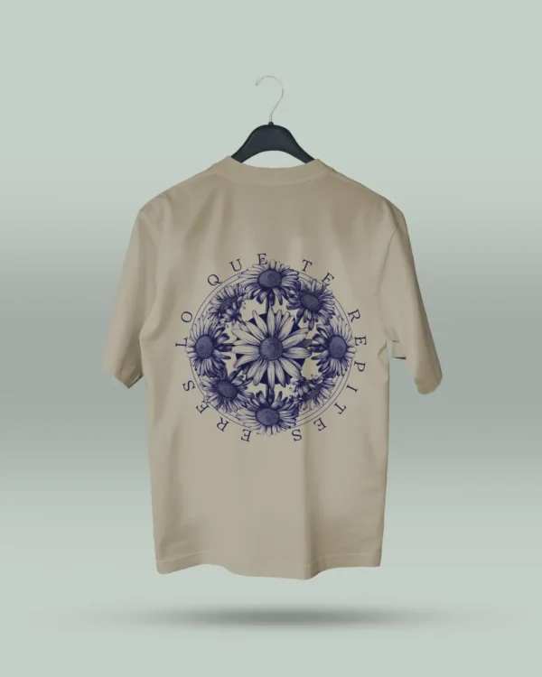 Camiseta beige unisex con ilustración artística de flores en círculo y la frase inspiradora Eres lo que te repites. Diseño exclusivo creado por ilustrador colombiano, ideal para quienes buscan ropa original con mensajes motivadores. Disponible en tallas varias y con envíos a todo Colombia.