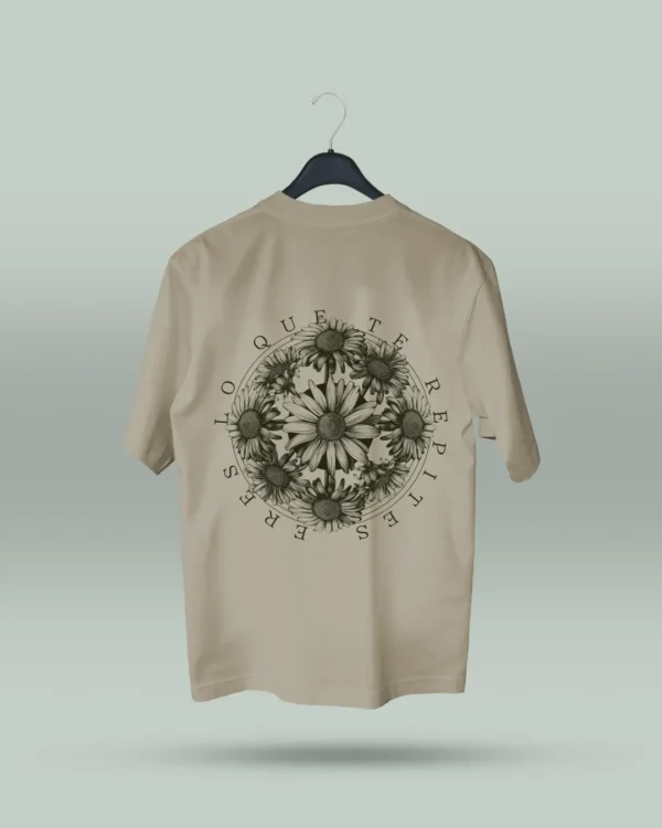 Camiseta beige unisex con ilustración artística de flores en círculo y la frase inspiradora Eres lo que te repites. Diseño exclusivo creado por ilustrador colombiano, ideal para quienes buscan ropa original con mensajes motivadores. Disponible en tallas varias y con envíos a todo Colombia.